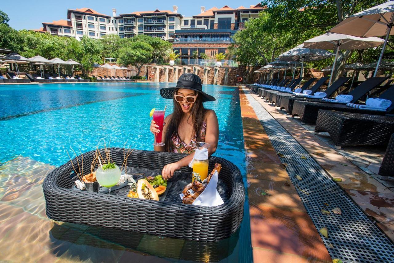 The Capital Zimbali Hotell Ballito Exteriör bild A woman at a poolside lounge